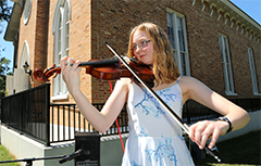 Female student playing violin outside of Bethel